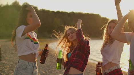 Teenagers-celebrate-a-birthday-on-the-beach-party-with-beer-and-good-mood.-They-clink-beer-and-dance-in-the-hot-evening.-This-is-carefree-party-at-sunset.